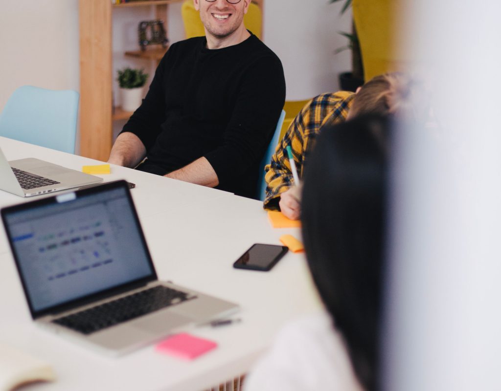 Homme souriant en face d’une personne qui écrit Homme souriant en face d'une personne qui écrit